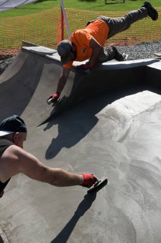 John Hogan, left, and Carl Guererro, top right, both of Hardwick, Vt., smooth the concrete on a feature of the Bethel, Vt., Skate Park, on Tuesday, Oct. 3, 2023. The first phase of the park was completed in 2020 and the second phase, started in early September by Parker Construction and expected to be completed by Nov. 1, roughly doubles its size. The Bethel Recreation Committee raised $25,000 to match a Land and Water Conservation Grant from the Vermont Department of Forests Parks and Recreation, and voters approved a contribution of $30,000 at Town Meeting to fund the $80,000 project. (Valley News - James M. Patterson) Copyright Valley News. May not be reprinted or used online without permission. Send requests to permission@vnews.com.