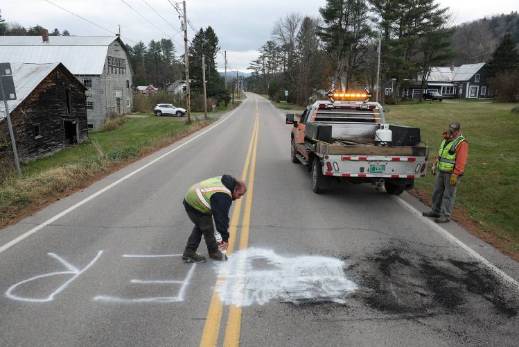 Eric Brown, left, and Luke Russ, right, of the Vermont Agency of Transportation, take time out from a ditching project to cover up a racial epithet spray painted on Route 14 in East Bethel, Vt., on Tuesday, Nov. 14, 2023. They plan to return with gray graffiti cover-up paint when they have the resources for a lane closure due to the paint’s long drying time. (Valley News - James M. Patterson) Copyright Valley News. May not be reprinted or used online without permission. Send requests to permission@vnews.com.