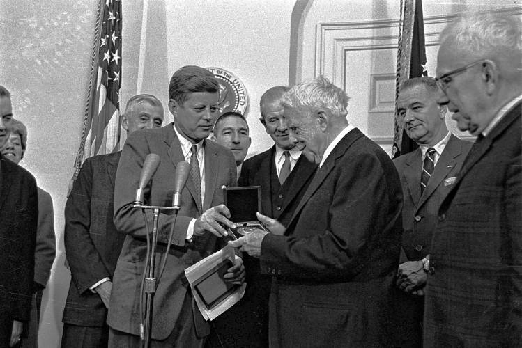 Poet Robert Frost looks at the congressional medal after it was presented to him March 26, 1962, by President John F. Kennedy at a White House ceremony.  The award was for his contribution to American letters.  The white haired poet, who is celebrating his 88th birthday, remarked, 