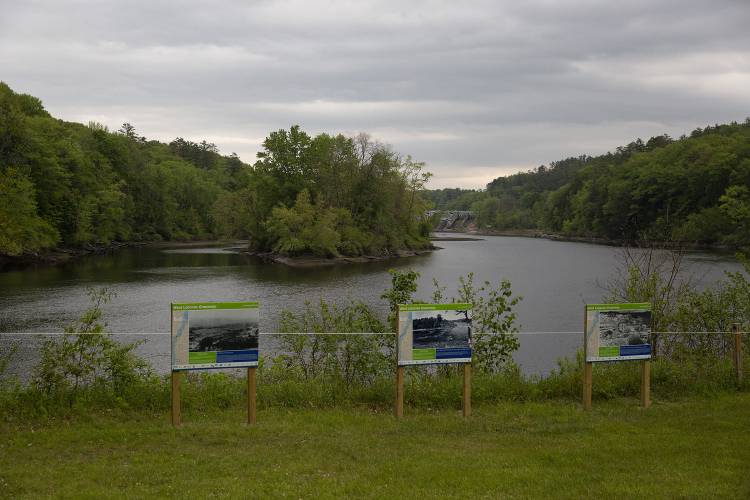 Signs display historical photos of the Wilder Dam alongside a map of the proposed West Lebanon Greenway, which would connect the Mascoma River Greenway to the trails around Boston Lot, at River Park in West Lebanon, N.H., on Wednesday, May 24, 2023. Part of Lyme Properties’ mixed-use development plan for the 38-acre lot includes two miles of trails and a publicly accessible waterfront park. (Valley News / Report For America - Alex Driehaus) Copyright Valley News. May not be reprinted or used online without permission. Send requests to permission@vnews.com.