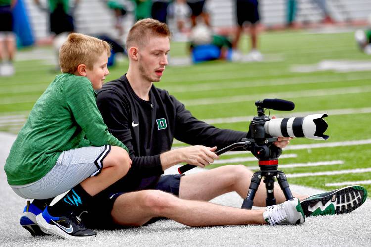 Cade Bettinger, creative content manager for the Dartmouth College football team, shows Patrick O'Dea an image on his camera screen during an Aug. 19, 2023, practice on Memorial Field. O'Dea is the son of Big Green running backs coach Danny O'Dea. (Valley News - Tris Wykes) Copyright Valley News. May not be reprinted or used online without permission. Send requests to permission@vnews.com.