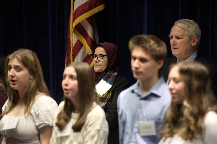 Judge Anisa Rasooli, center, Paul Reiber, chief justice of the Vermont Supreme Court, right, listen to the Hanover High School chorus sing the Star Spangled Banner during an event to honor Rasooli and judge Geeti Roeen in Hanover, N.H., on Thursday, Jan 4, 2024. Rasooli, who now lives in Vermont, presided over cases of corruption and violence against women, and was an unconfirmed appointee to the Afghan Supreme Court when she was forced to flee the country during the U.S. withdrawal. (Valley News - James M. Patterson) Copyright Valley News. May not be reprinted or used online without permission. Send requests to permission@vnews.com.