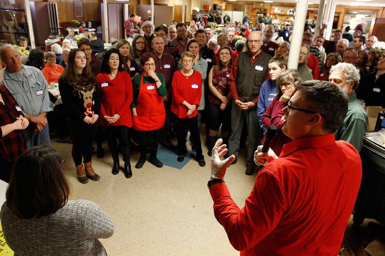 Listen Community Services Executive Director Kyle Fisher speaks with volunteer servers about a change in how the annual Lebanon Christmas Day Dinner was to be presented to those in attendance in the basement of Sacred Heart Church in Lebanon, N.H., on Dec. 25, 2018. (Valley News - Geoff Hansen) Copyright Valley News. May not be reprinted or used online without permission. Send requests to permission@vnews.com.