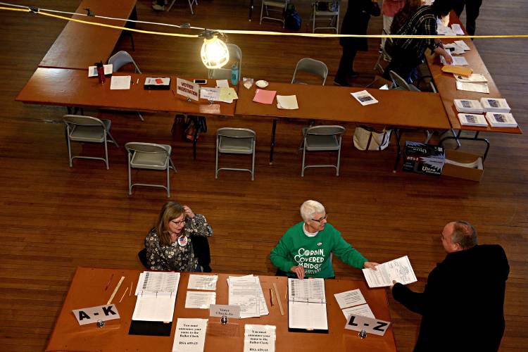 Newport ballot clerks Sandra Cherry, left, and Jacqueline Cote hand ballots to voters on Tuesday, March, 12, 2019 in Newport, N.H. With ballot in hand voter Mark Pitkin is on his way to the voting booth. (Valley News - Jennifer Hauck) Copyright Valley News. May not be reprinted or used online without permission. Send requests to permission@vnews.com.