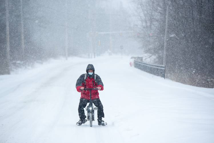 Adam Aupperlee commutes by electric bike from his job as a baker at Dartmouth Hitchcock Medical Center in Lebanon, N.H., to the Upper Valley Haven in White River Junction through an early spring snow storm on Saturday, March 23, 2024. He said he plans to move out of the Haven in April. The storm dropped up to 20 inches of snow over the area by 4 p.m. on Saturday. (Valley News - James M. Patterson) Copyright Valley News. May not be reprinted or used online without permission. Send requests to permission@vnews.com.