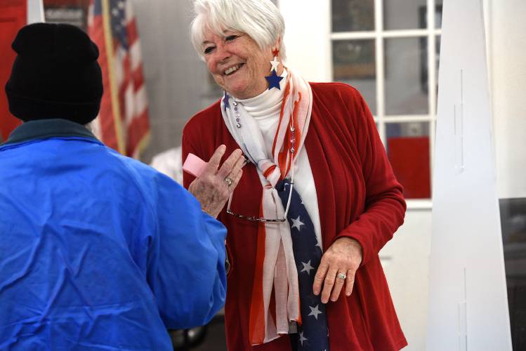 At the Canaan, N.H., polls, voter Freda Washburn gives ballot clerk Debbie McDermott a pat on the shoulder on Tuesday, Jan. 23, 2023. McDermott was dressed in red white and blue for the day. 