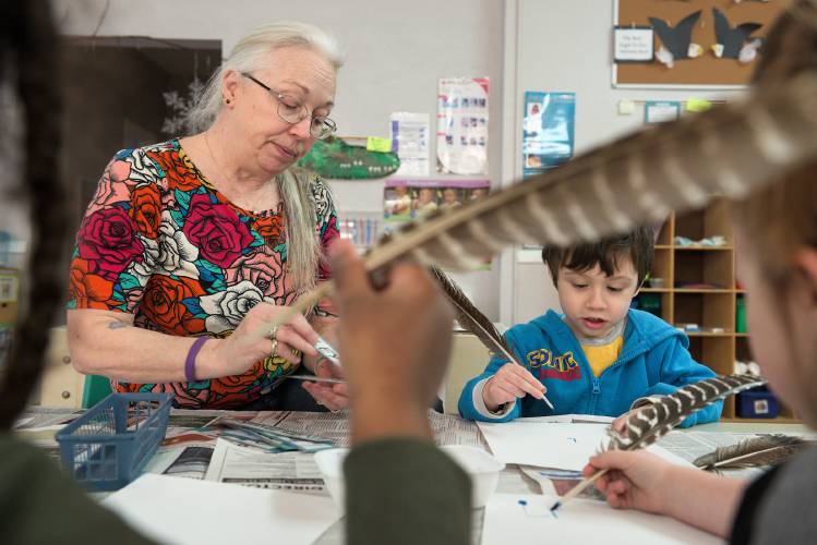 Lead Teacher Susan Brown, left, helps Lucas Collins, 4, right, Ezekiel McNeil, 4, left, and Livian Franks, 5, right, write their names with quill pens at Children’s Place Preschool in Windsor, Vt., on Thursday, Feb. 29, 2024. Brown also serves as center manager for Children's Place and practice based coach, supporting teachers at two more Head Start preschools in Windsor County. With the closure of the Windsor center in May, Brown will transition to full time in the coaching position. (Valley News - James M. Patterson) Copyright Valley News. May not be reprinted or used online without permission. Send requests to permission@vnews.com.