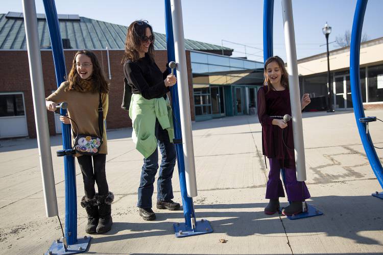 Chelly Shaw, center, of Chepachet, R.I., plays hot cross buns on giant chimes with her nieces Alyson, 11, left, and Anna, 8, both of New London, N.H., at the Harmony Park musical playground at the Lebanon Mall in Lebanon, N.H., on Tuesday, Feb. 27, 2024. Shaw is in town for an upcoming family ski trip and spent the day outdoors with the girls taking advantage of the warm weather. (Valley News / Report For America - Alex Driehaus) Copyright Valley News. May not be reprinted or used online without permission. Send requests to permission@vnews.com.