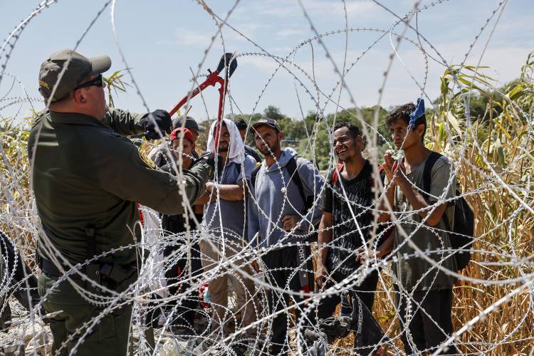 A border patrol agent cuts razor wire to allow migrants who've been waiting in the sun for hours to come to a way station under the Camino Real International Bridge, Sept. 24, 2023. (Robert Gauthier/Los Angeles Times/TNS)