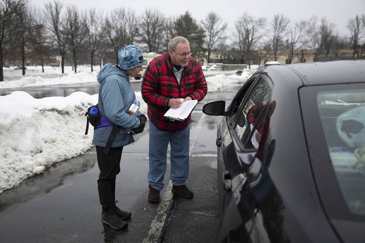 Stacey Chiocchio, left, community citizenship manager at Hypertherm, and Roscoe Putnam, communications coordinator at Listen Community Services, interview a man living in his car during a Point-in-Time Count in the Walmart parking lot in West Lebanon, N.H., on Thursday, Jan. 25, 2024. The annual survey, mandated by the U.S. Department of Housing and Urban Development, is conducted nationwide by local organizations to collect data on the number of people experiencing homelessness on a given night in January, which is used to inform funding and policy decisions around homelessness. (Valley News / Report For America - Alex Driehaus) Copyright Valley News. May not be reprinted or used online without permission. Send requests to permission@vnews.com.