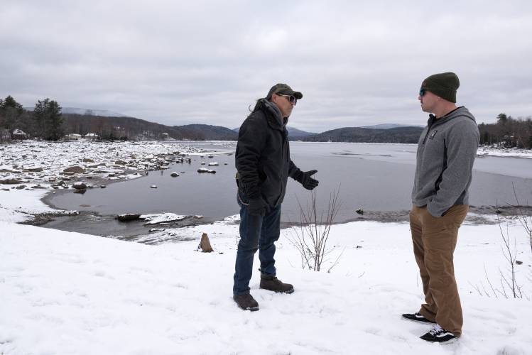 Army veterans Patrick Swain, of Canaan, left, and Richard Robinson, of Colorado, right, talk after a chance meeting in the parking lot on the dam overlooking Goose Pond in Canaan, N.H., where they came to look at the drop in water level on Tuesday, Dec. 5, 2023. The pond is being drawn down by the New Hampshire Department of Environmental Services’ Dam Bureau to facilitate repairs that will be ongoing into 2025. “I used to come out here and swim across the lake,” said Robinson, who was visiting his parents in Canaan and wanted to photograph the lake. (Valley News - James M. Patterson) Copyright Valley News. May not be reprinted or used online without permission. Send requests to permission@vnews.com.