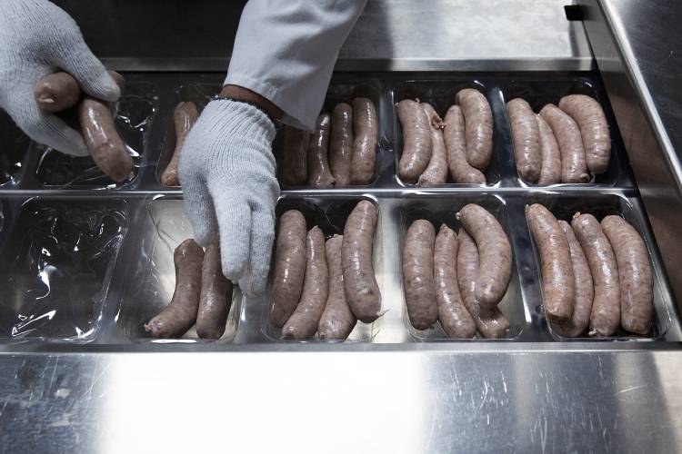Shawn Fletcher places sausages into containers to package them for sale at Granite State Packing in Claremont, N.H., on Tuesday, July 18, 2023. The sausages were part of an order for Vermont Salumi, based in Barre, Vt., one of the packing co-op’s three main customers. (Valley News / Report For America - Alex Driehaus) Copyright Valley News. May not be reprinted or used online without permission. Send requests to permission@vnews.com.