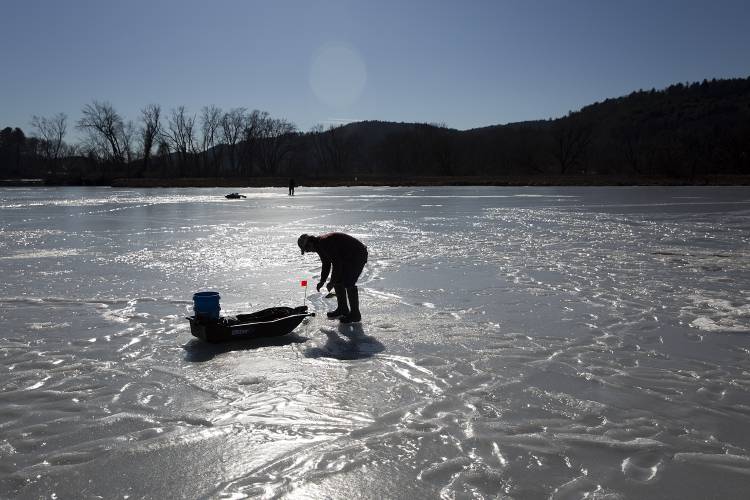 Scott Bashaw, of Springfield, Vt., baits one of his tip ups while ice fishing at White’s Cove near the confluence of the Black and Connecticut rivers in Springfield on Thursday, Feb. 8, 2024. The warm sun and 45 degree weather left a layer of slush on some parts of the ice, but it was still about six inches thick. Bashaw, who says he has been fishing at the cove “since I was born,” claims there was a time in the 1970s when the ice was so thick he had to weld an extension onto his auger to drill through it. (Valley News / Report For America - Alex Driehaus) Copyright Valley News. May not be reprinted or used online without permission. Send requests to permission@vnews.com.