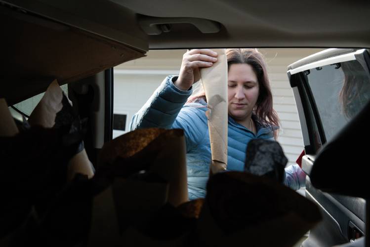 Krista Patronick, of Hanover, takes a rose from the back of her car to bring to a widow in Plainfield, N.H., on Valentine's Day, Feb. 14, 2024. Patronick and another friends who is also a widow delivered flowers to 30 widows and widowers around the Upper Valley. 